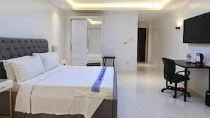 Habitación de hotel moderna con una cama grande, un escritorio y un televisor de pantalla plana.