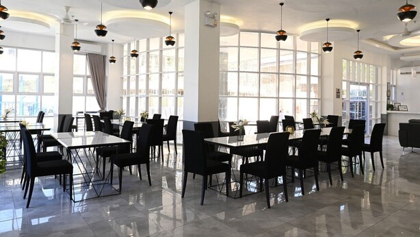 Un comedor amplio con techos altos, moderna iluminación colgante y grandes ventanales con vistas a la ciudad.