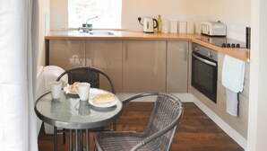 Eine kompakte Küche mit Essbereich, ausgestattet mit einem runden Tisch, Korbstühlen, einem Toaster und einem Wasserkocher.