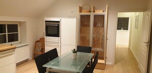 Uma cozinha compacta com mesa, cadeiras, geladeira e um armário de vidro.