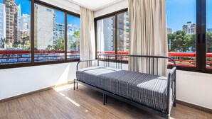 Een moderne hotelkamer met een eenpersoonsbed, grote ramen en uitzicht op de skyline.