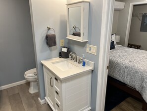A bathroom with a white vanity, a mirror, a towel rack, and a toilet.
