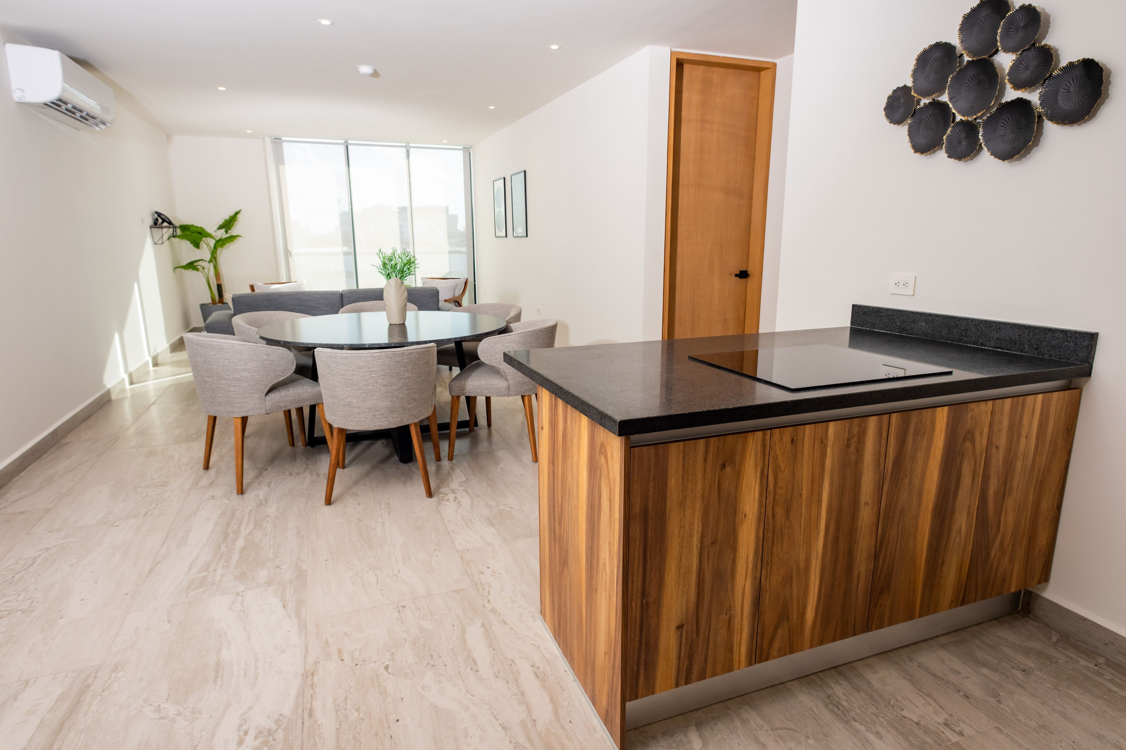 A modern kitchen with a wooden island, a dining area with a round table and chairs, and a large window providing natural light.
