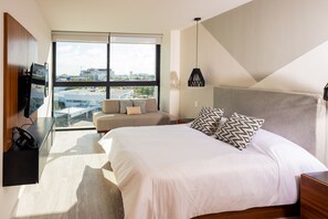 Una habitación de hotel moderna con una cama grande, un sofá, un escritorio y un televisor.
