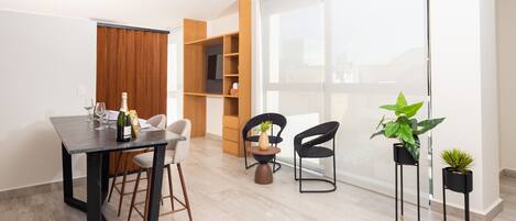 Un espace repas moderne avec une table, des chaises et un téléviseur en arrière-plan.
