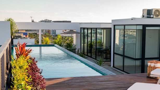 Ein Pool auf dem Dach mit einer Holzterrasse, umgeben von üppiger Bepflanzung und moderner Architektur.