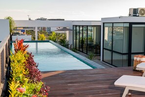 A rooftop pool with a wooden deck, surrounded by lush plants and modern architecture. - Torre Sofia Cancun (Cancun)