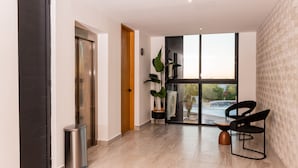 Ein modernes Interieur mit einer Holztür, einem Mülleimer, einem Blumentopf und einer Sitzecke mit Tisch und Stühlen.