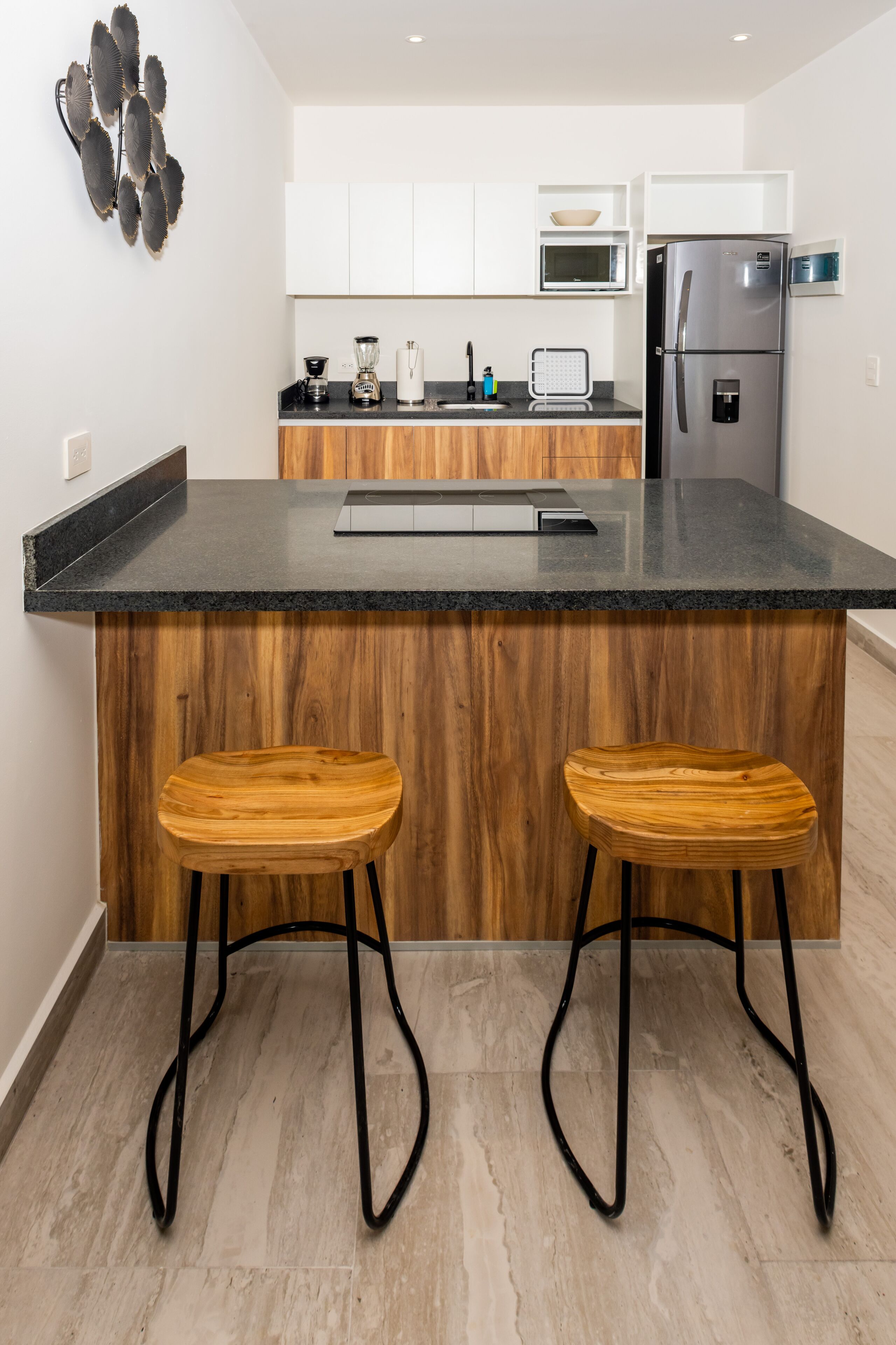 Une cuisine moderne dotée d’un îlot central, de tabourets en bois et d’appareils électroménagers en acier inoxydable.