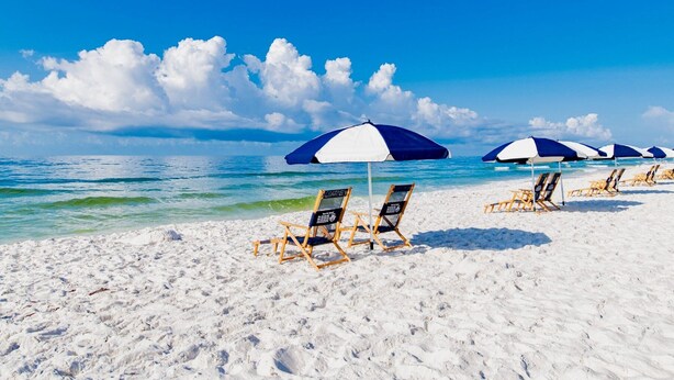 A beach with white sand, clear blue water, and a row of beach chairs and umbrellas. - Summer House 1402B | Direct beach front! Oversized deck! Great location! (Orange Beach)