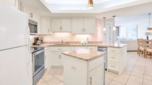 A modern kitchen with white cabinets, granite countertops, and stainless steel appliances. - Summer House 1402B | Direct beach front! Oversized deck! Great location! (Orange Beach)
