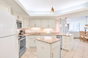 A modern kitchen with white cabinets, granite countertops, and stainless steel appliances.
