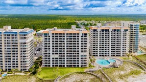 A high-rise hotel with multiple floors, a central courtyard, and a circular pool area. - Summer House 1402B | Direct beach front! Oversized deck! Great location! (Orange Beach)