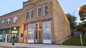 A stone building with a ground-floor entrance and upper-floor windows. - Downtown Experience Rich in History & Charm! Centrally Located in Black Hills (Whitewood)