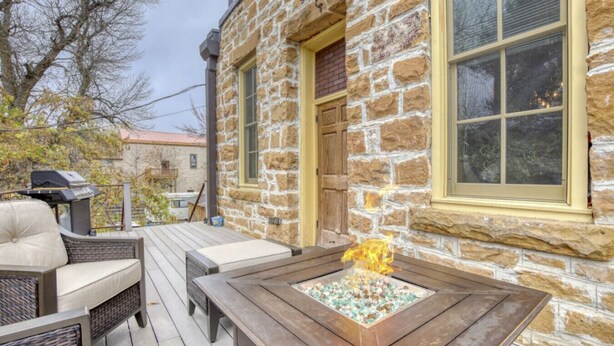 A stone building with a deck, outdoor seating, and a fire pit. - Downtown Experience Rich in History & Charm! Centrally Located in Black Hills (Whitewood)
