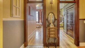 A hallway with wooden doors, a mirror, and a light fixture. - Downtown Experience Rich in History & Charm! Centrally Located in Black Hills (Whitewood)