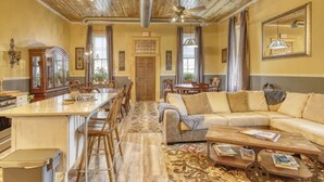 A spacious living area with a large sofa, a coffee table, and a dining area with chairs and a table. - Downtown Experience Rich in History & Charm! Centrally Located in Black Hills (Whitewood)