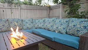 Un patio con una chimenea integrada y un sofá de mimbre con cojines azules.