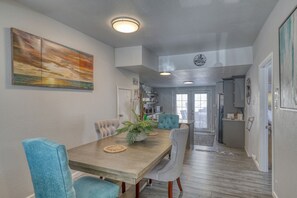 A dining area with a wooden table, six chairs, and a large painting on the wall. - A Private, Stunning Home Walking Distance to Food, Drinks, & Parks (Whitewood)