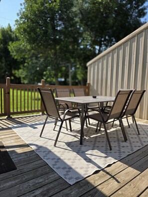 A wooden deck with a table and chairs, surrounded by a wooden fence and trees. - A Private, Stunning Home Walking Distance to Food, Drinks, & Parks (Whitewood)