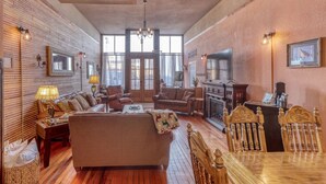 A spacious living room with a fireplace, comfortable seating, and a dining area with a wooden table and chairs. - Truly the GOAT! Hot tub, Pet friendly, Walk to bar/restaurant, Quiet, Unique (Whitewood)