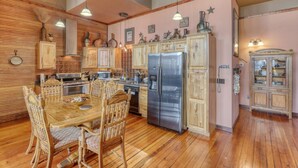 A kitchen with wooden cabinets, a stainless steel refrigerator, and a dining table with chairs. - Truly the GOAT! Hot tub, Pet friendly, Walk to bar/restaurant, Quiet, Unique (Whitewood)