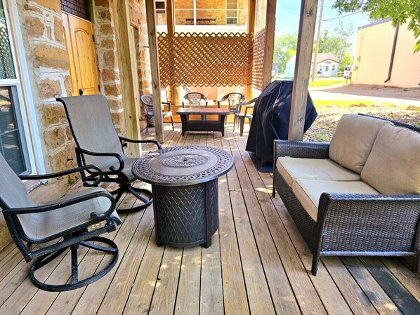 A wooden deck with wicker furniture, including a round table and two chairs. - Truly the GOAT! Hot tub, Pet friendly, Walk to bar/restaurant, Quiet, Unique (Whitewood)