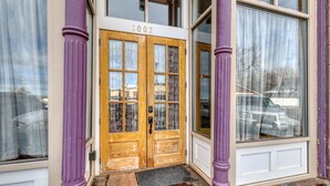 A building entrance with a double wooden door, numbered 1007, flanked by purple columns, and a doormat at the entrance. - Truly the GOAT! Hot tub, Pet friendly, Walk to bar/restaurant, Quiet, Unique (Whitewood)