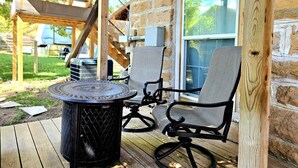 An outdoor patio with a round table and two chairs, a wooden staircase, and a stone wall. - Truly the GOAT! Hot tub, Pet friendly, Walk to bar/restaurant, Quiet, Unique (Whitewood)