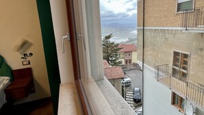 Una habitación con vistas a un paisaje urbano a través de una ventana, suelo de madera y pared verde.