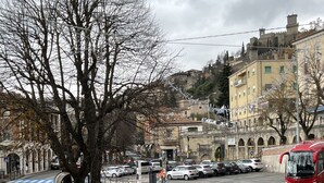 Una calle urbana con un autobús, coches aparcados y edificios.