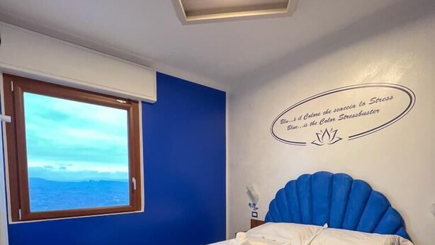 Un dormitorio con cama, ventana y lámpara en el techo.