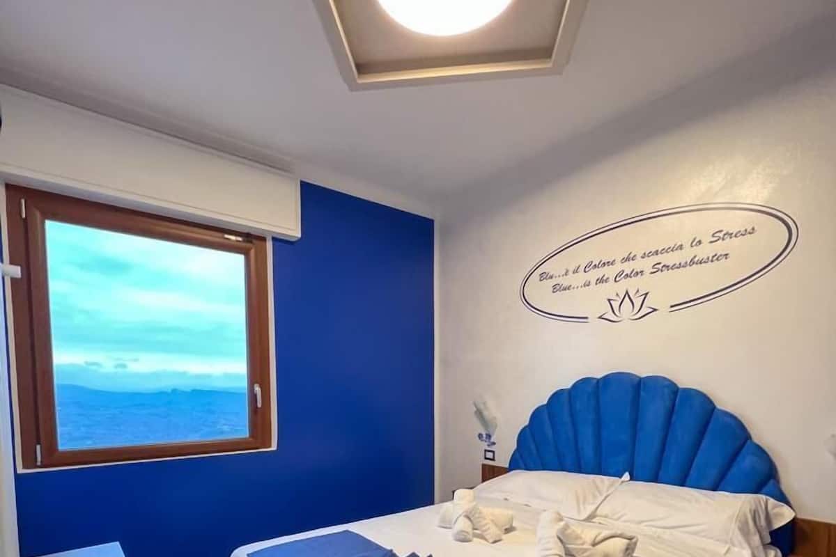 A bedroom with a bed, a window, and a ceiling light.
