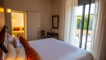 Une chambre d’hôtel avec un grand lit, un bureau, une chaise, un miroir et une vue sur l’extérieur grâce à une porte-fenêtre coulissante.