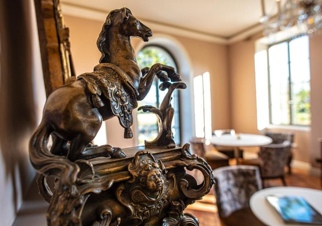 An ornate metal sculpture of a horse in a well-lit room with a round table and chairs.