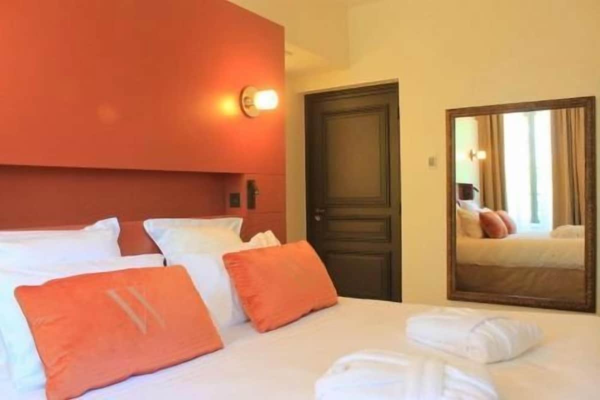 Een hotelkamer met een bed, kussens, een deur en een spiegel.