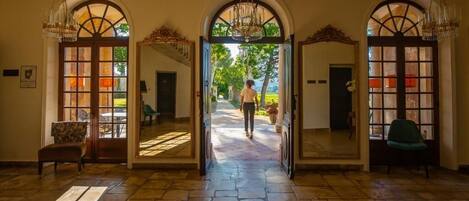A grand entrance with arched doorways, a stone floor, and a chandelier.