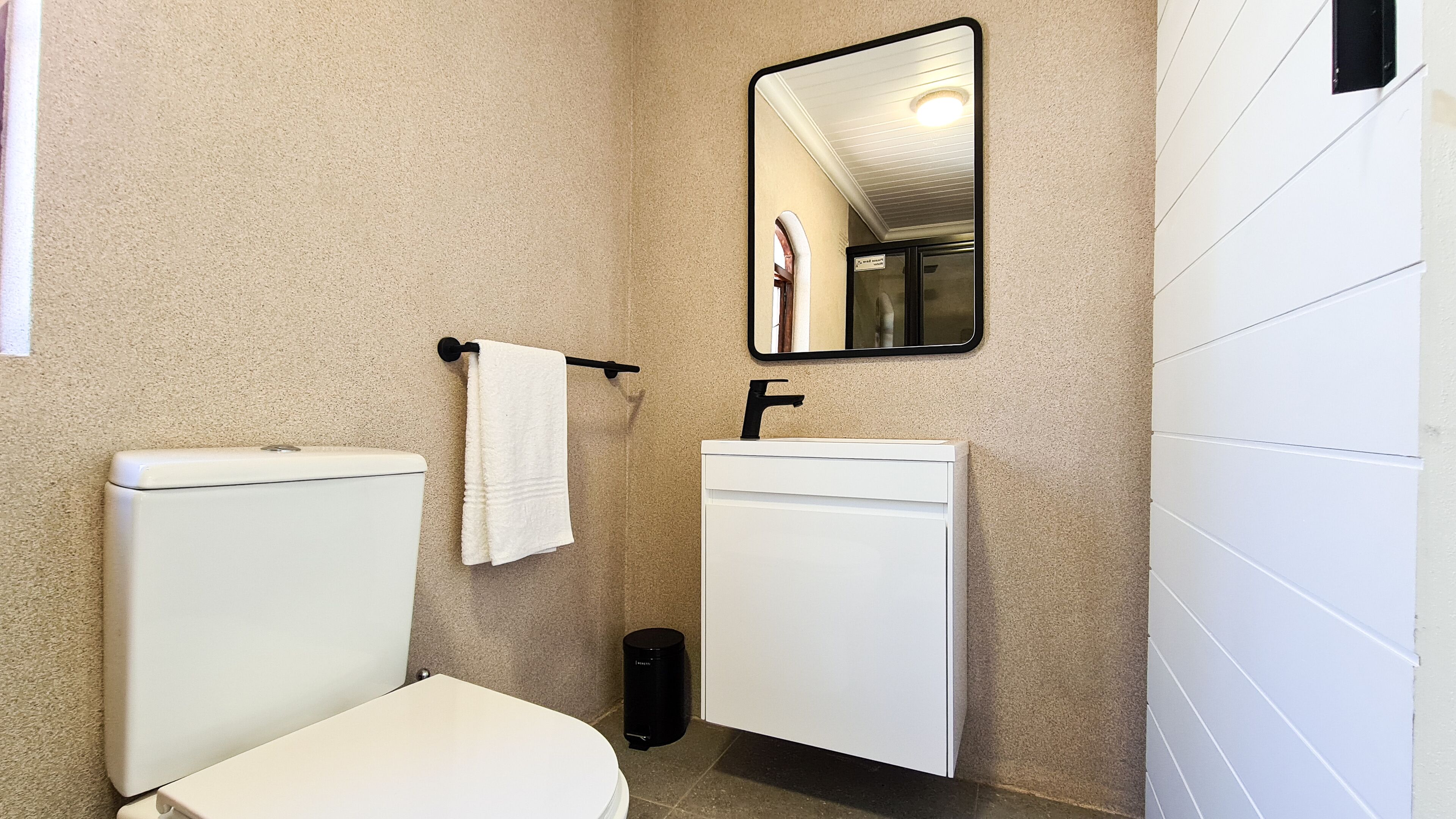 Un baño con inodoro, lavamanos y espejo.
