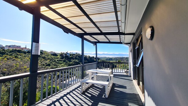 A balcony with a wooden deck, white benches, and a metal railing. - Vincent Valley Lodge (East London)