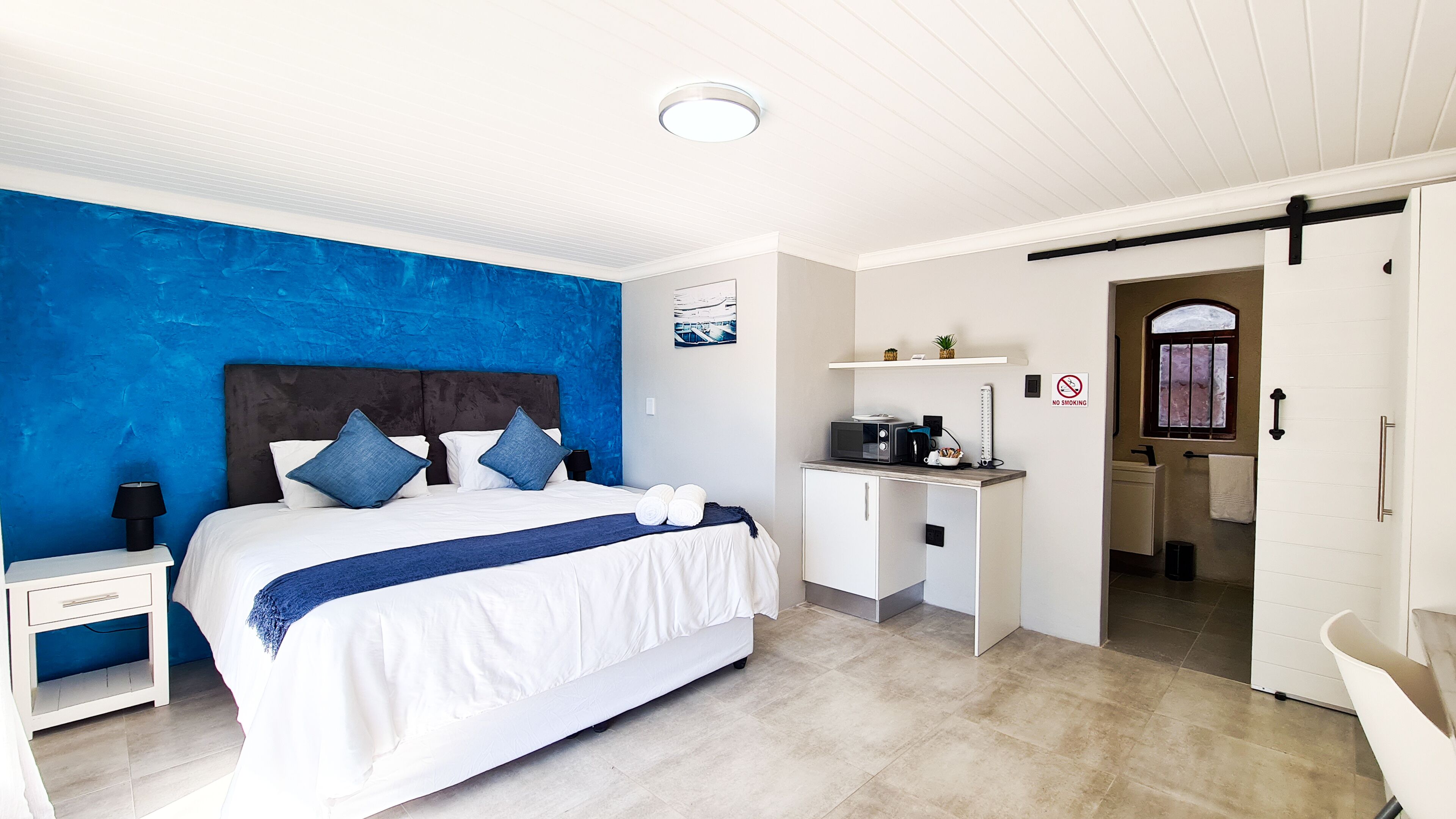 A modern hotel room with a large bed, a desk, and a bathroom.