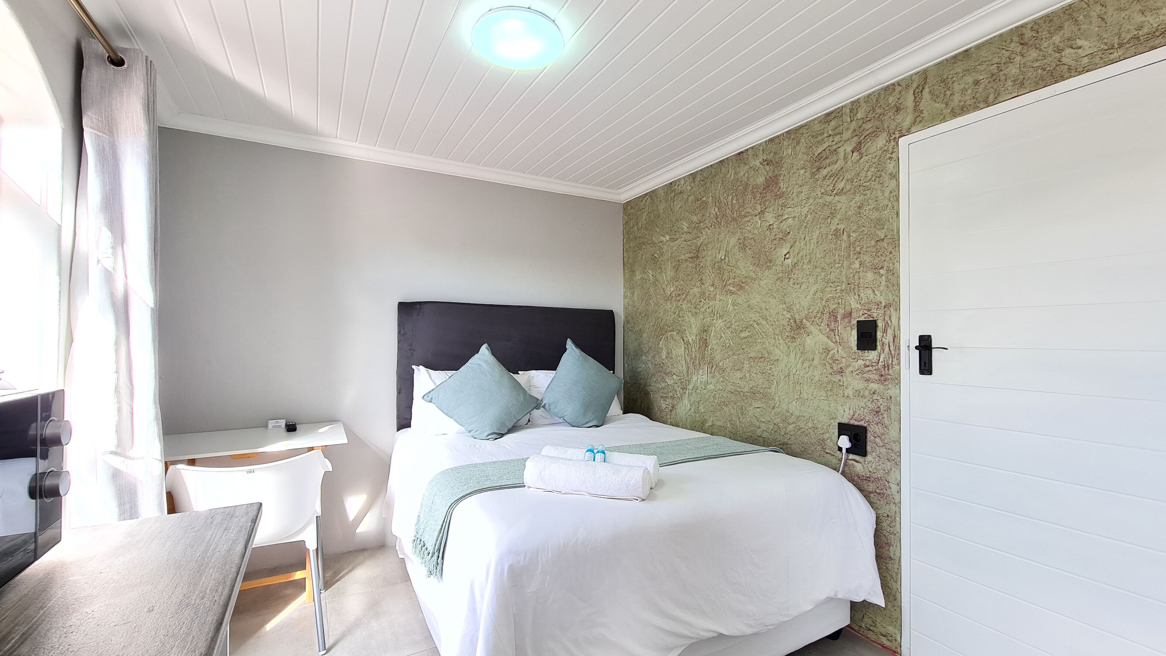 A neatly arranged bedroom with a bed, bedside table, and a chair.