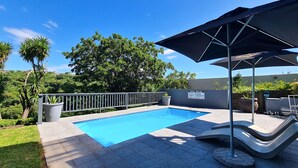 A swimming pool with a poolside area, a metal railing, and a sign with pool rules. - Vincent Valley Lodge (East London)