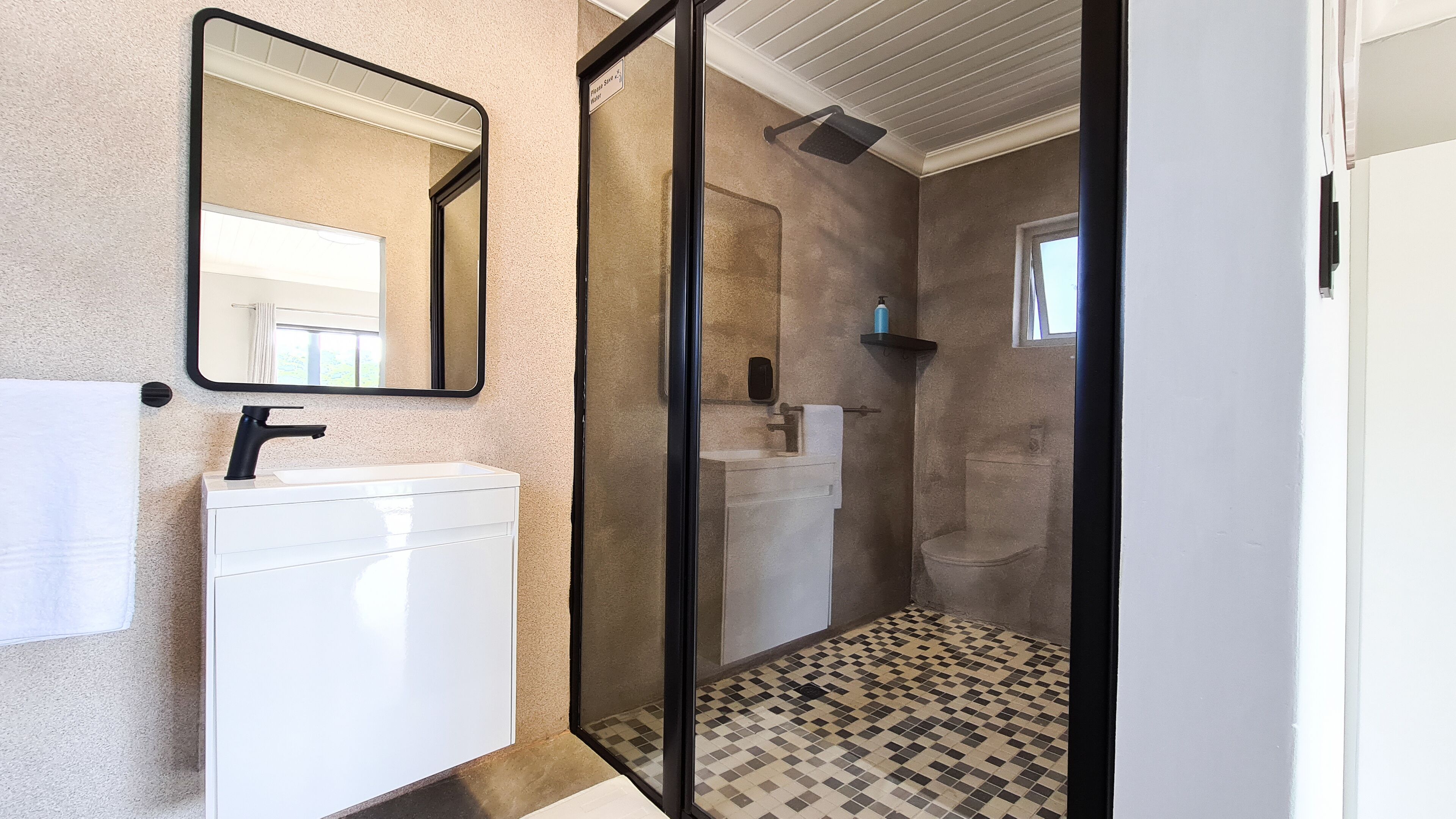 A bathroom with a white sink, a mirror, and a shower area.