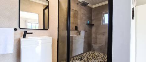 A bathroom with a white sink, a mirror, and a shower area.