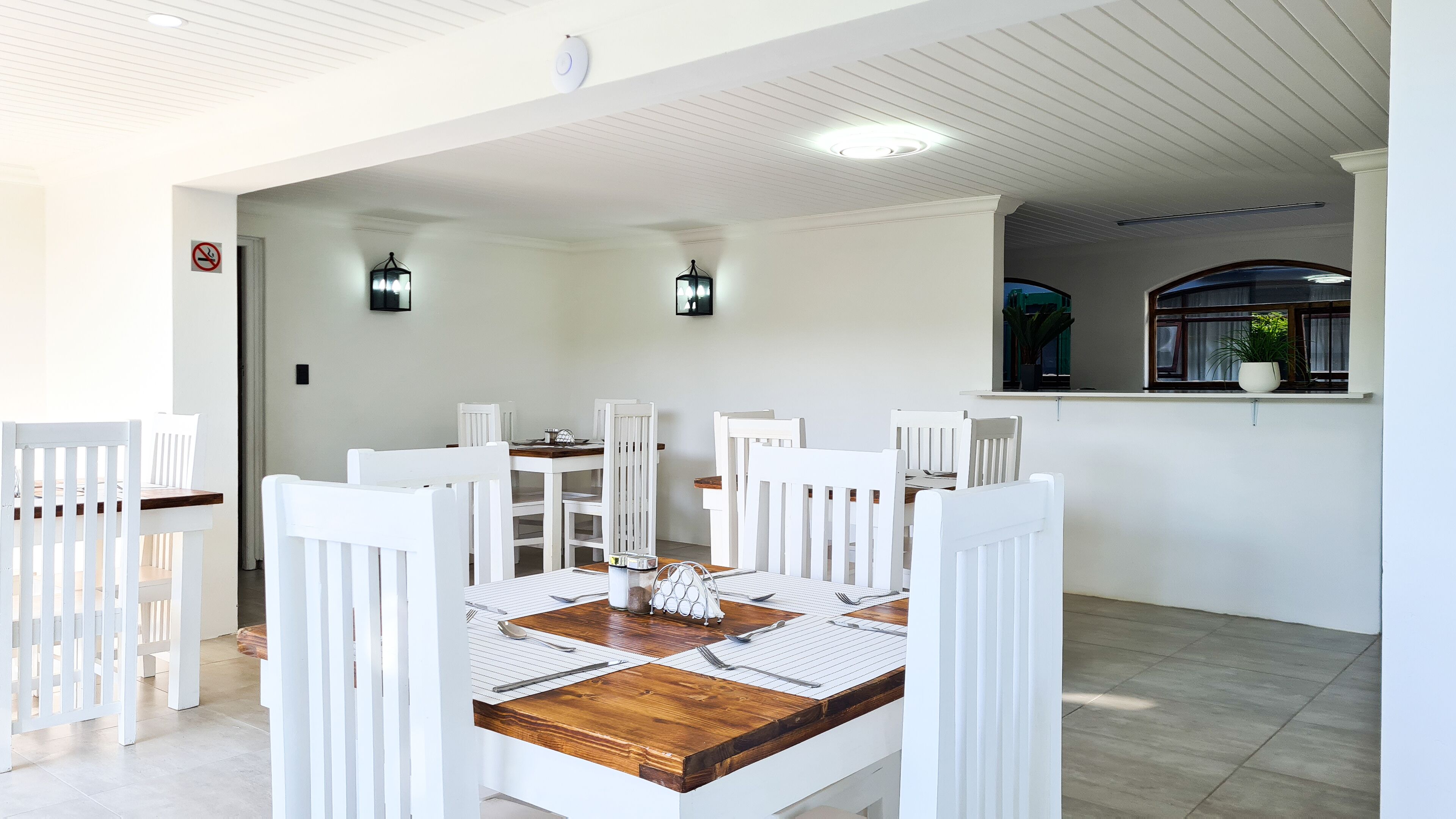 Comedor con una mesa de madera dispuesta para cuatro personas, rodeada de sillas blancas.