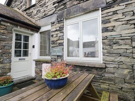 Un edificio de piedra con puerta de madera, una ventana con persianas y un cartel que dice 'Jenny's 2 Croft Barn'.