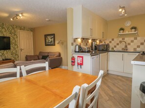 A compact kitchen with a dining area, a sofa, and a flat-screen TV. - Jenny's (Ambleside)