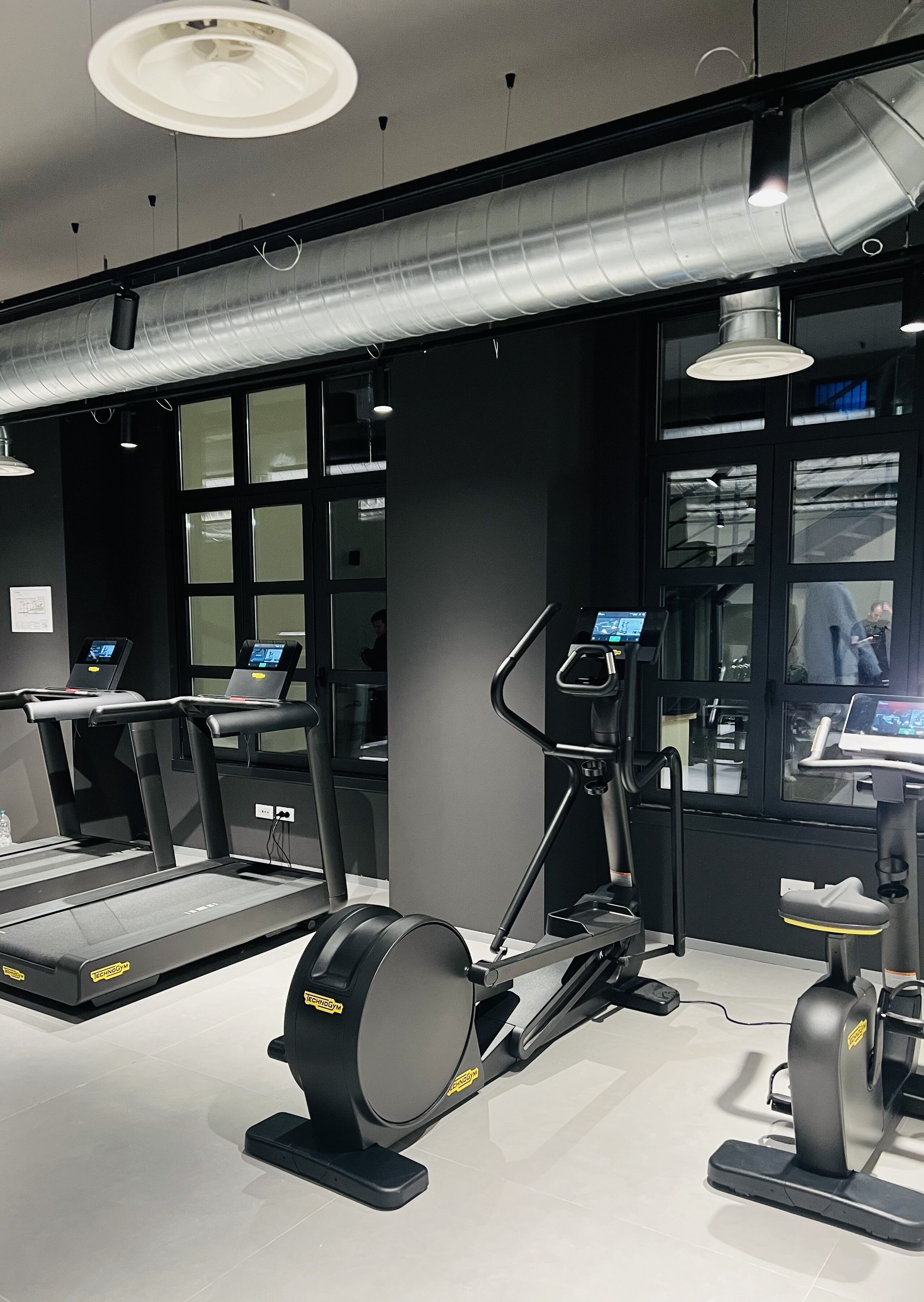 Een sportschool met loopbanden, een elliptische trainer en een hometrainer.