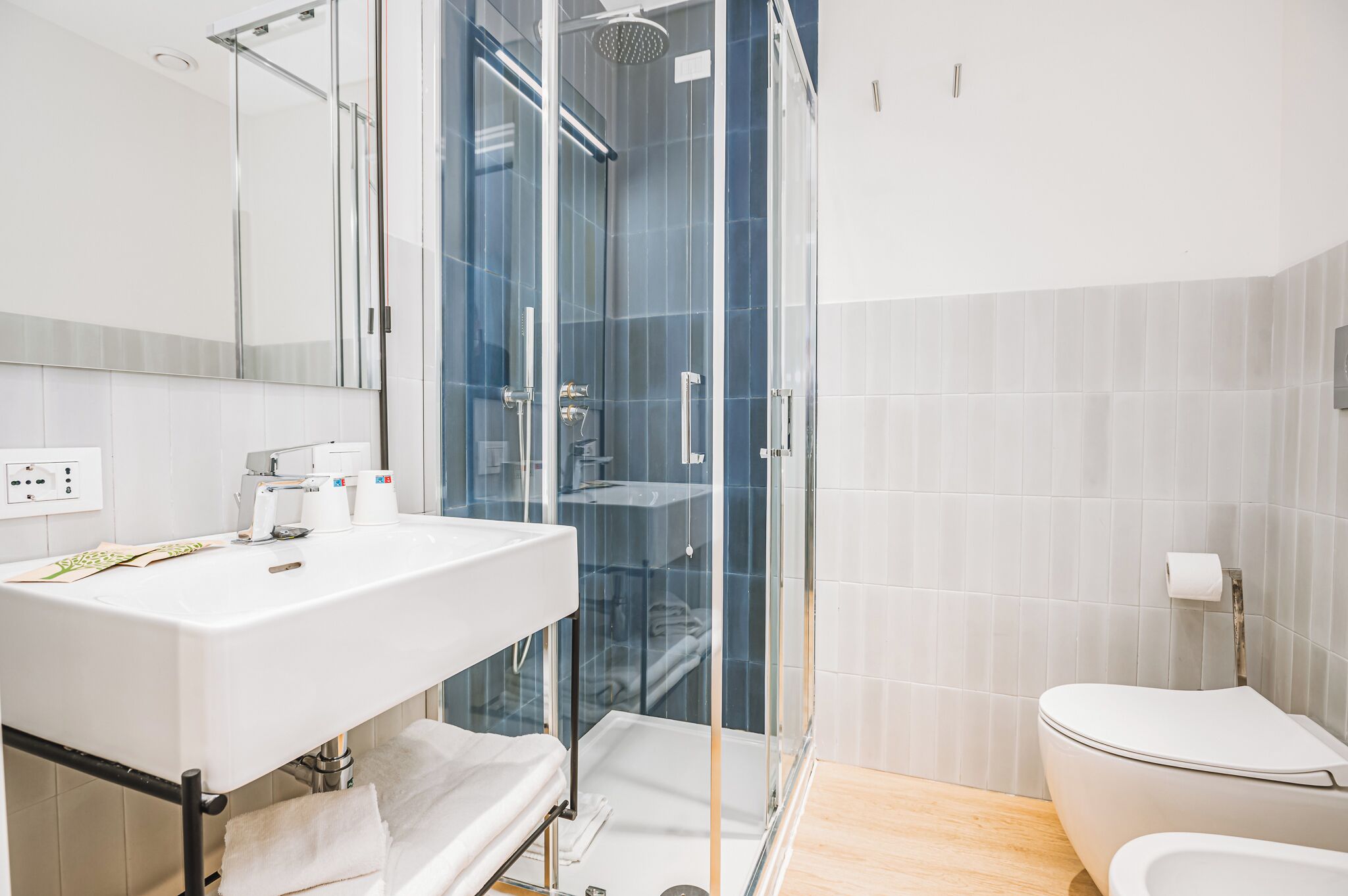 A modern bathroom with a glass-enclosed shower, a white sink, and a toilet.