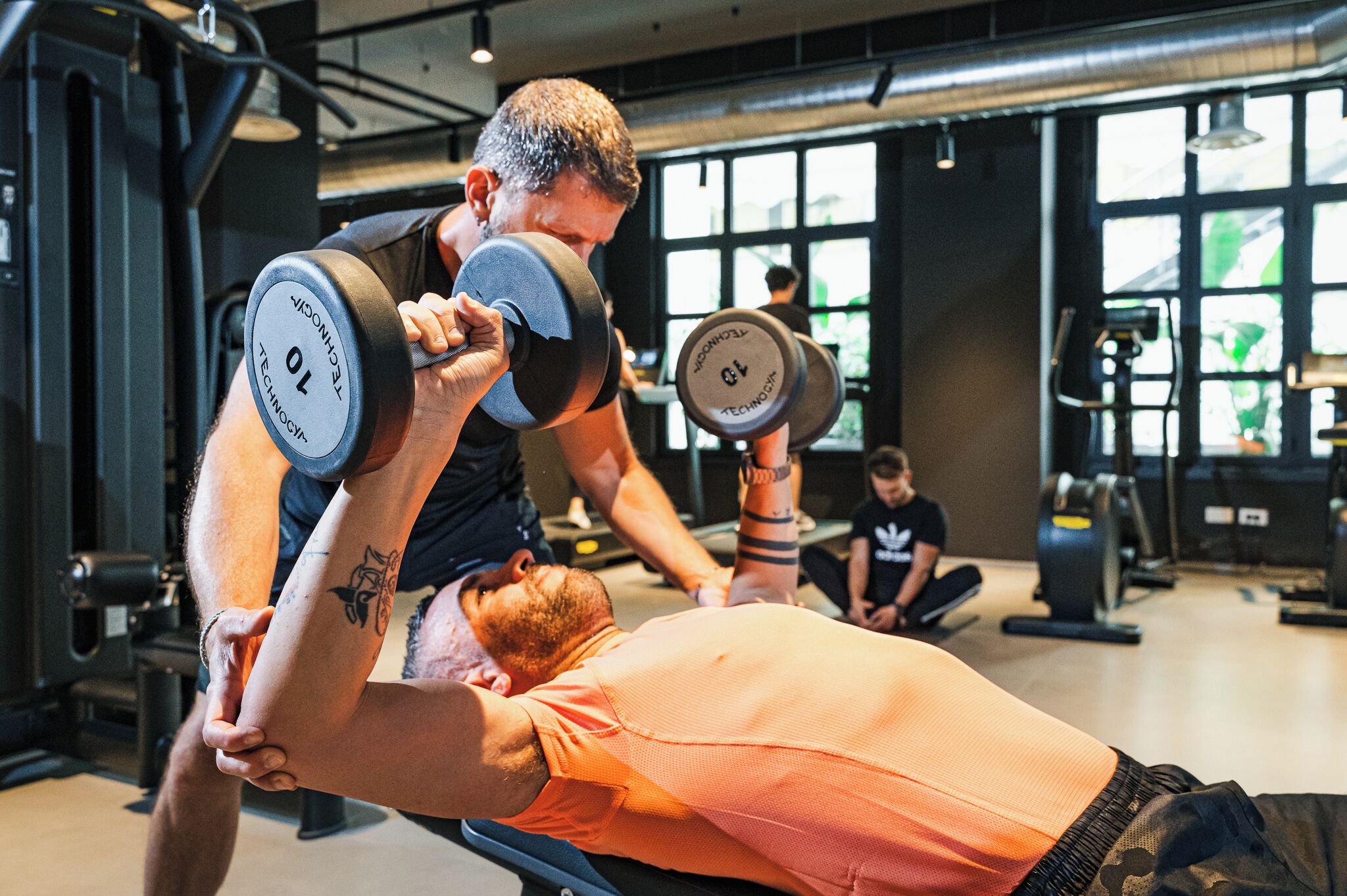 A gym with a person performing a bench press exercise.